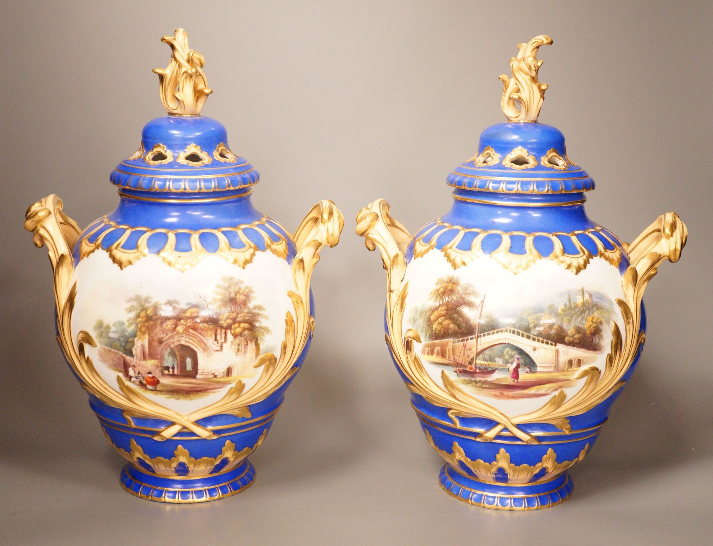 A pair of English bone China lidded two-handled vases, painted with river landscapes, within blue and gilt fields, circa 1840, 33cm